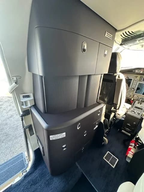 View of the aircraft cabin with storage cabinets and a table.