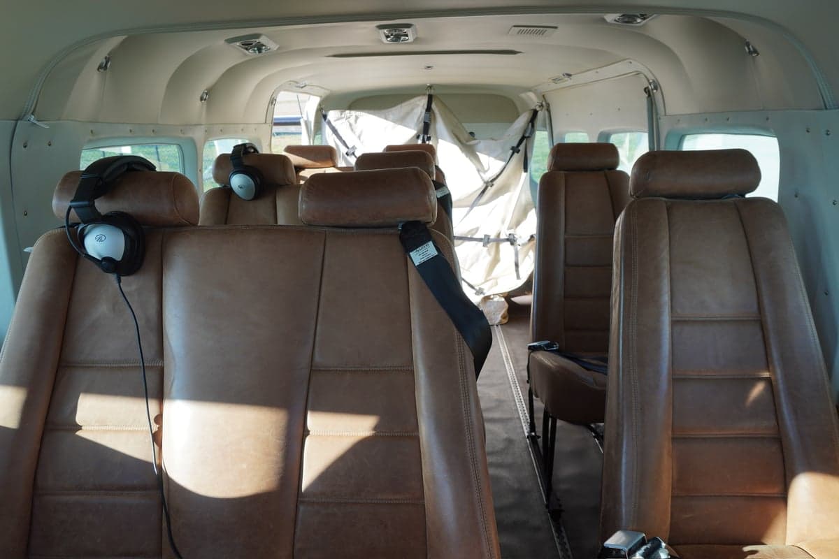 The interior cabin of a Cessna Caravan, featuring multiple rows of brown leather passenger seats.