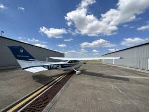 Cessna 172 Skyhawk, registration N759CB, parked on the tarmac in front of a hangar.