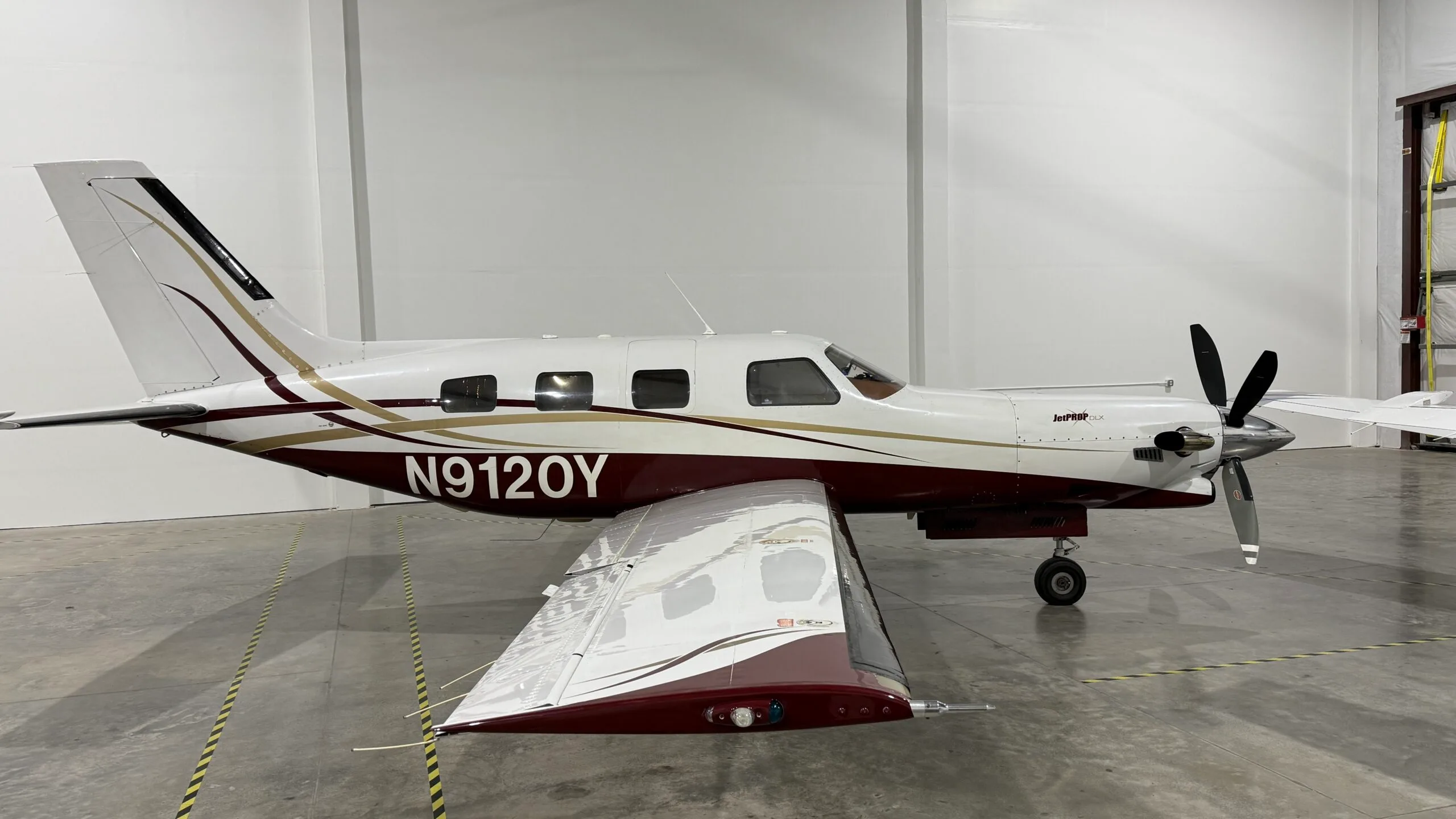 A white and maroon JetPROP aircraft with registration N9120Y parked in a hangar.
