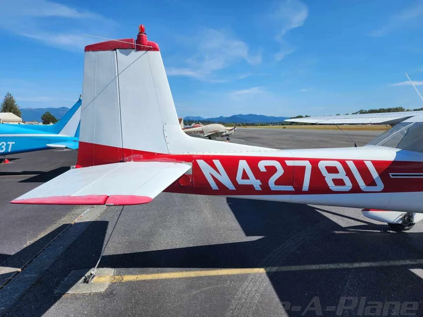 The tail section of a white and red Cessna 150 aircraft with registration N4278U parked on an airfield.