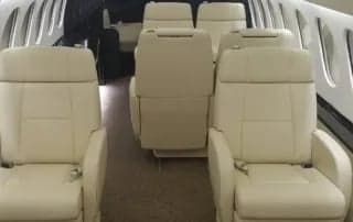 Interior view of the aircraft cabin with cream-colored leather seats.