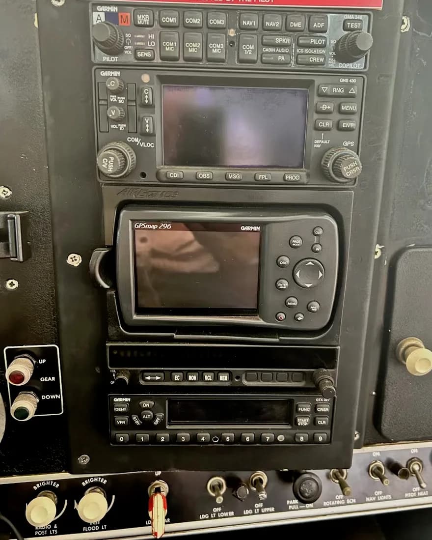 A close-up view of an aircraft's avionics stack, featuring multiple Garmin radios and GPS units.