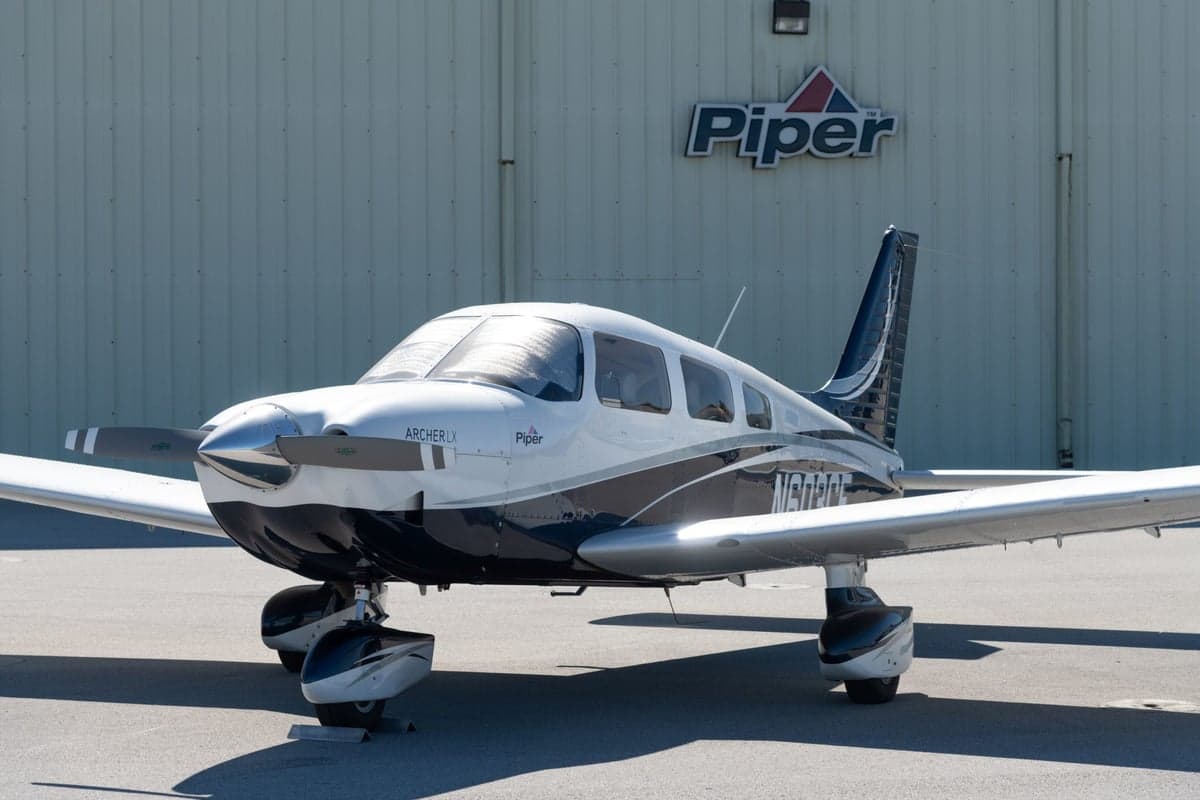 Front view of the Piper Archer LX N603CE in front of a hangar with the Piper logo.