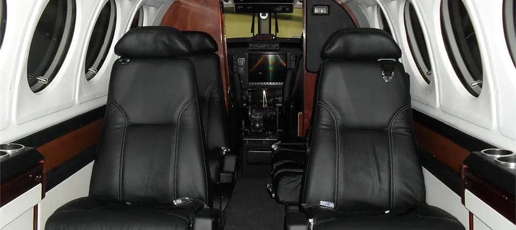Interior view of the aircraft cabin with leather seats and cockpit in the background.