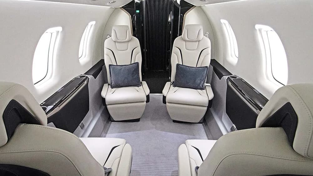 Interior view of the aircraft cabin with cream-colored leather seats and dark wood trim.