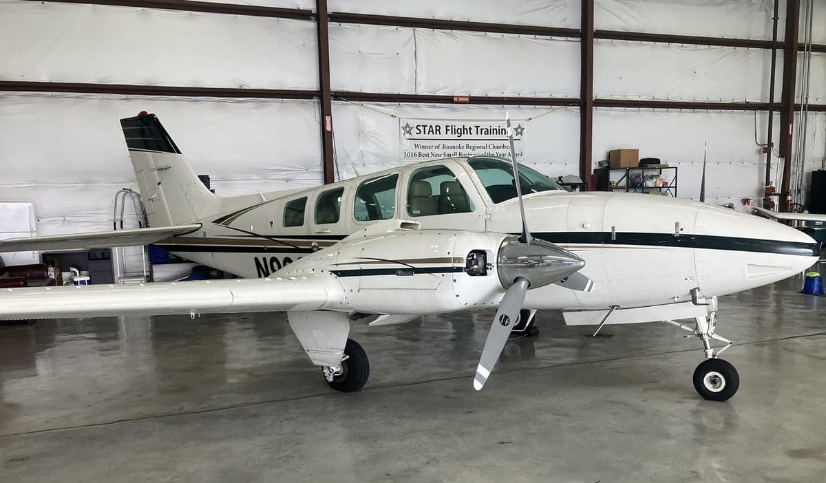 A white and brown Beechcraft Baron with registration N9929Y parked in a hangar.