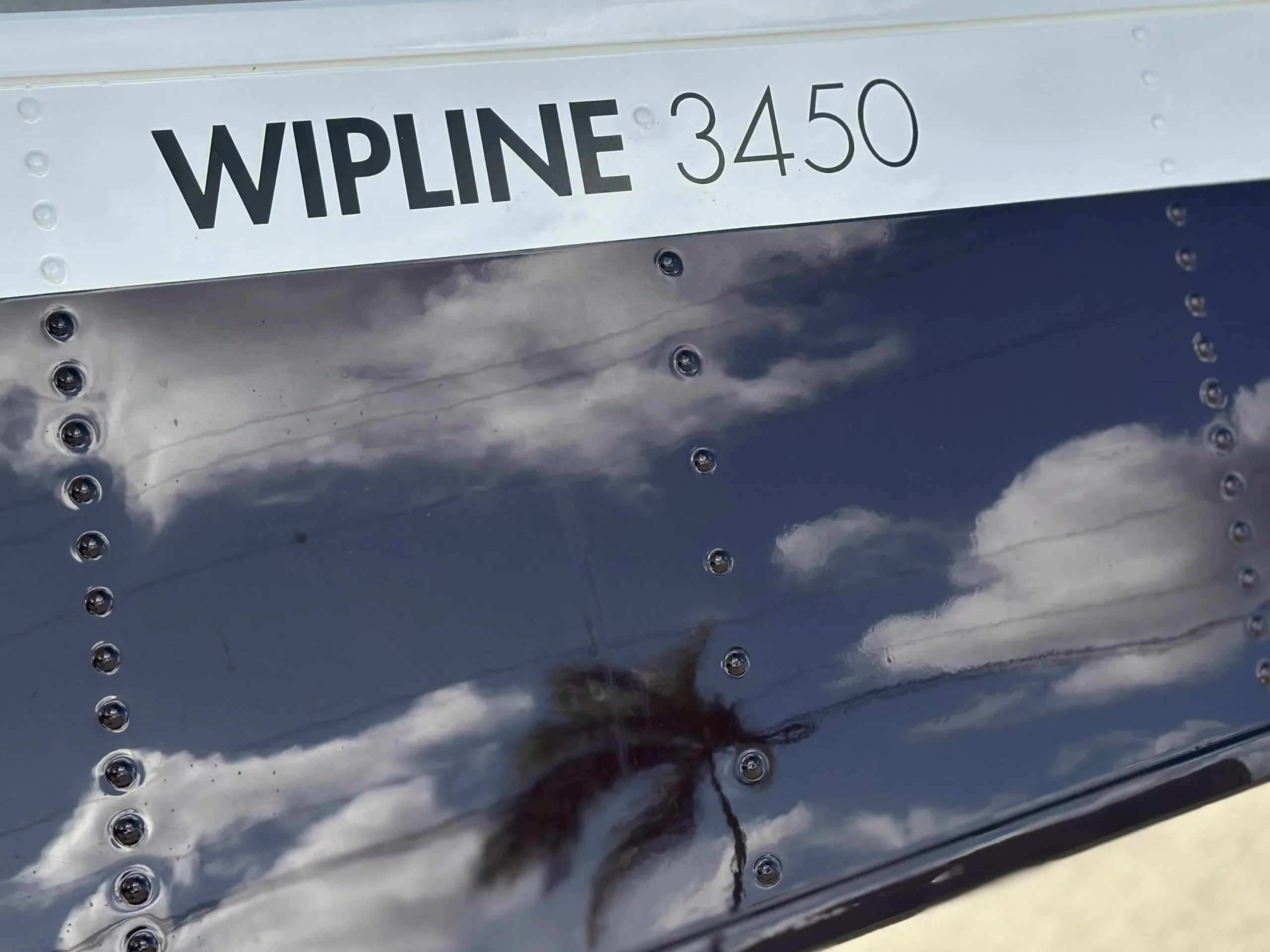 A close-up of the aircraft's float, showing 'WIPLINE 3450' text and sky reflections.