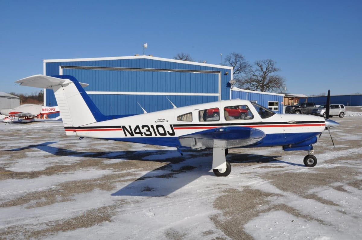 Piper Arrow on a snowy ramp, side view.