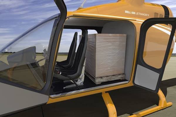A yellow Bell 505 JetRanger X with the doors open, showing the interior and cargo space.