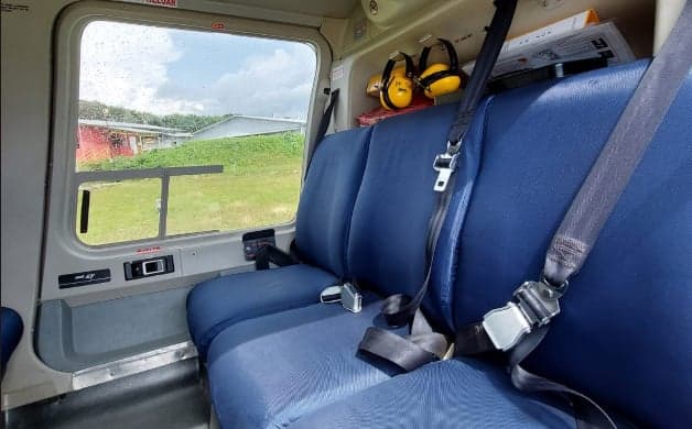 Helicopter interior with blue seats and yellow headphones.