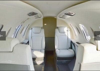 The aircraft's interior features white leather seats and a spacious cabin.