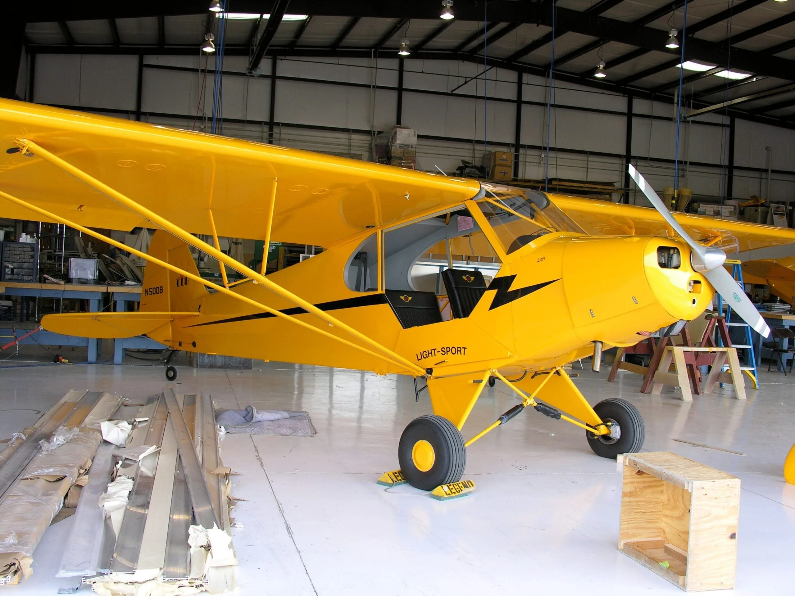 A yellow Light-Sport aircraft (N503B) with black stripes is parked inside a hangar.