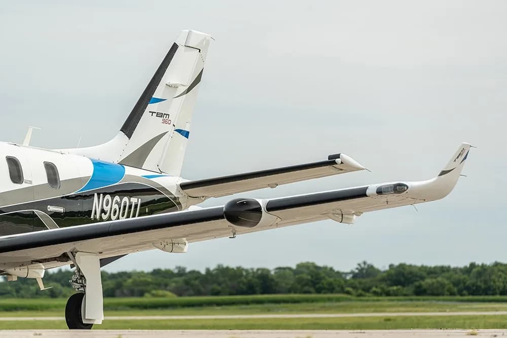 A rear side view of the TBM 960 turboprop aircraft, registration N960TL, showing its tail and wing.