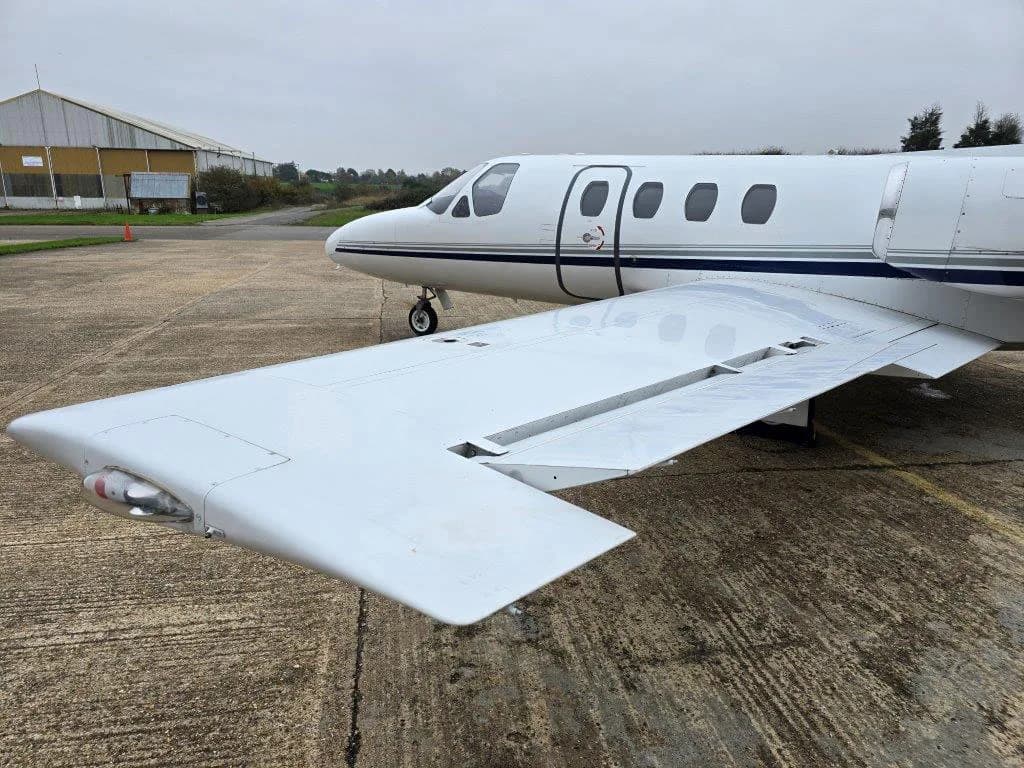 A close-up view of the wing and mid-fuselage of a white Cessna Citation jet.