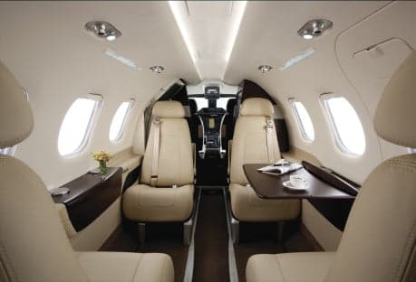 A Phenom 100 aircraft on the runway with a white and black paint scheme.