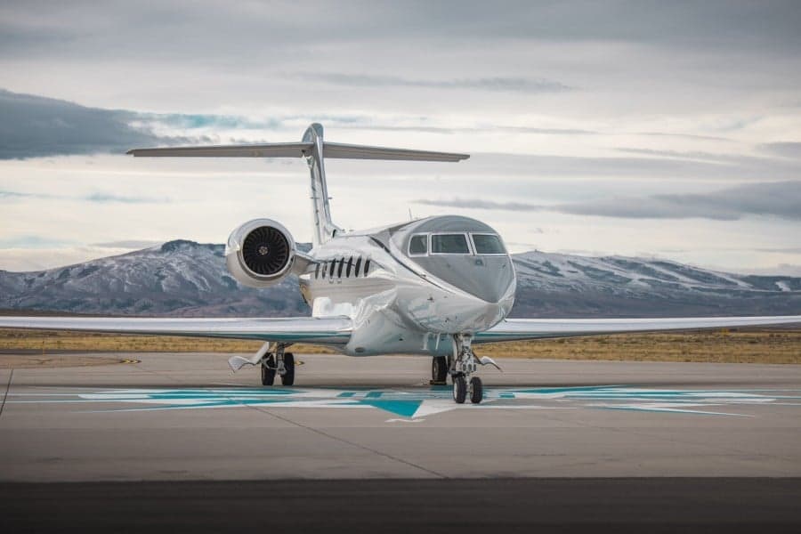 Front view of a Gulfstream aircraft on the tarmac with mountains in the background.