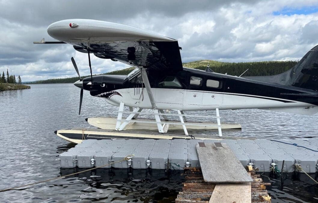 Seaplane with shark teeth paint scheme docked on a lake.