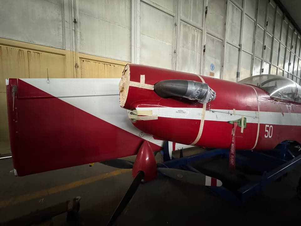 A23-050 aircraft in a hangar with red and white paint scheme.