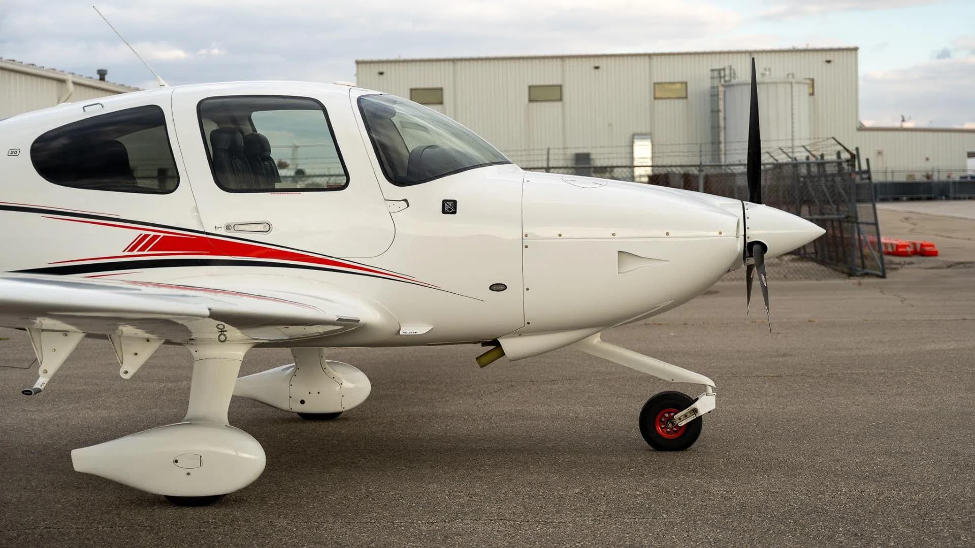 A side view of the front section of the white Cirrus SR22 aircraft, highlighting the propeller and nose landing gear.