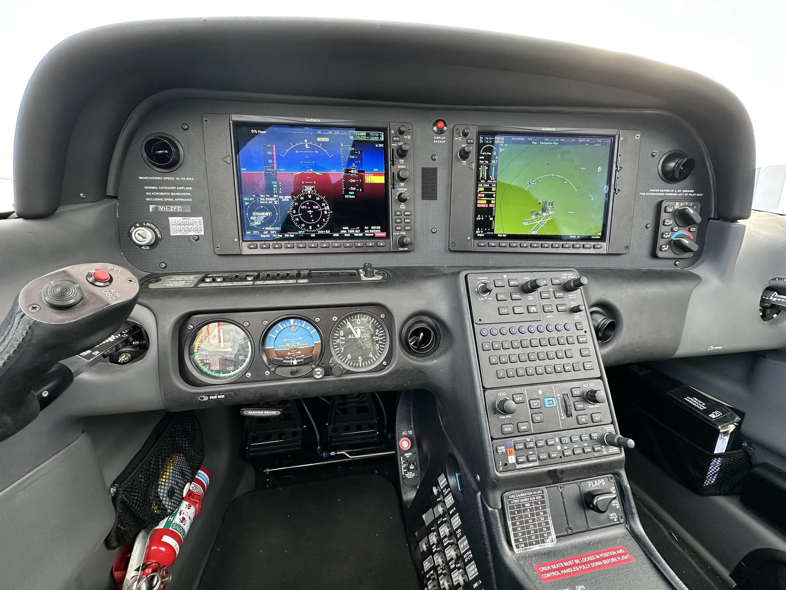 The cockpit of a modern aircraft featuring two large glass displays, traditional gauges, and a control yoke.