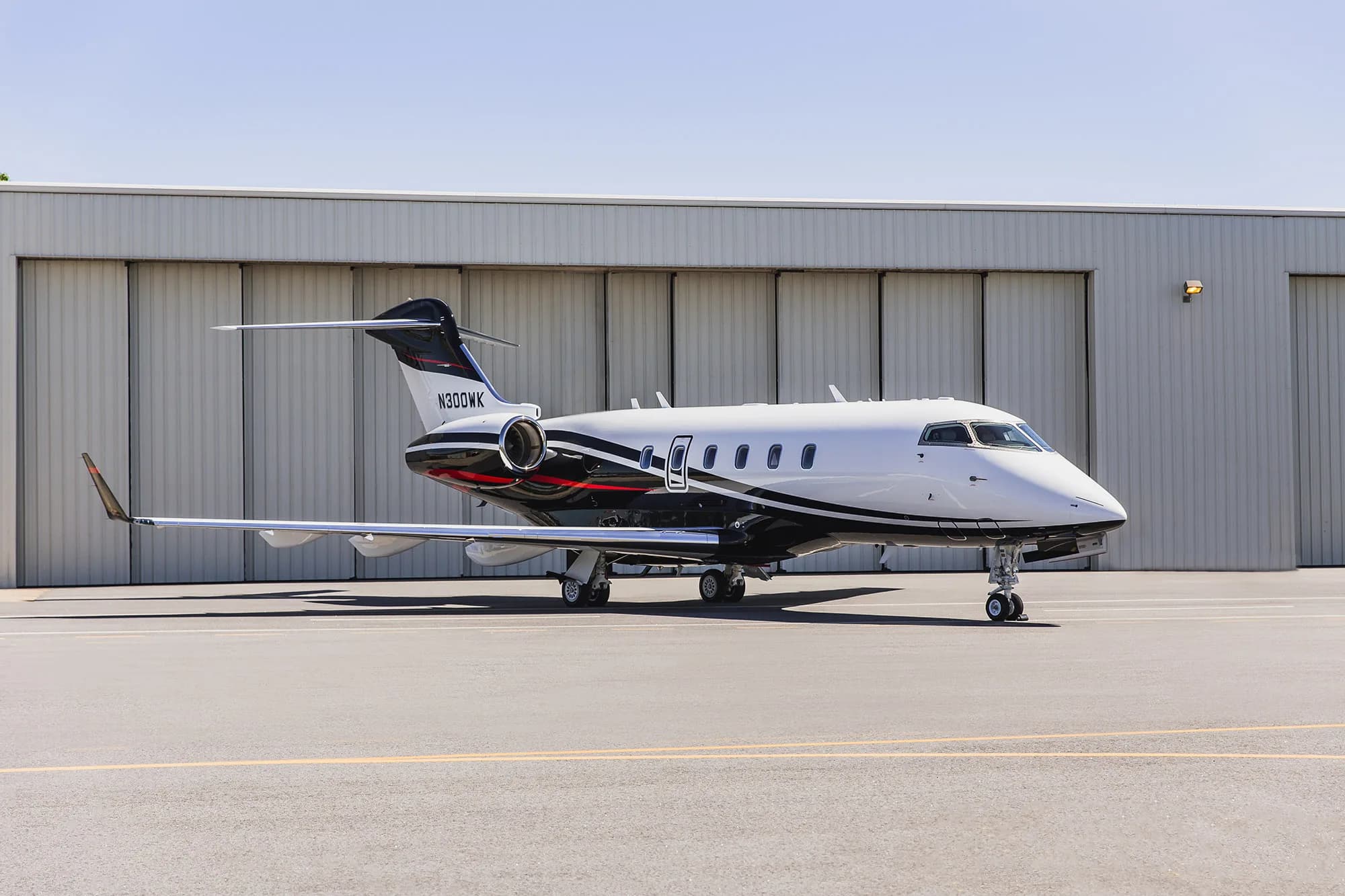 Aircraft N300WK parked in front of a hangar.