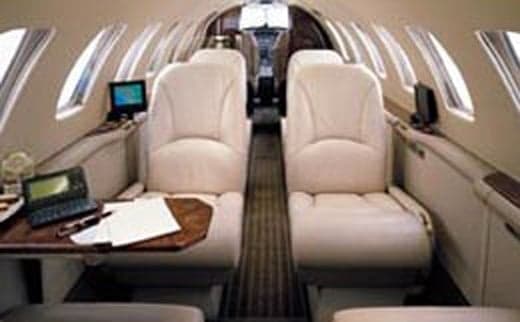 The interior of the aircraft features cream-colored leather seats and wood trim.