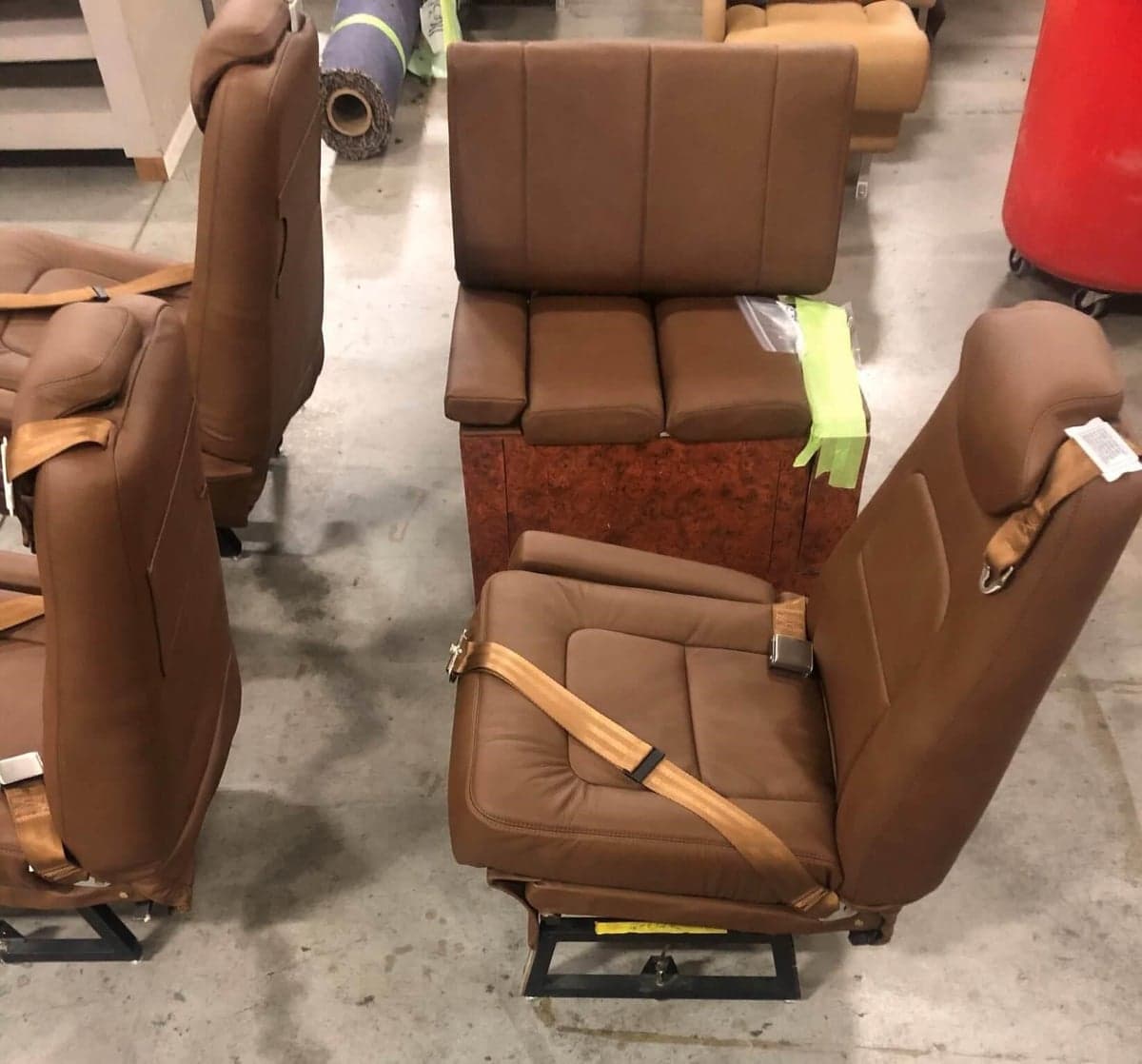 Aircraft seats with brown leather upholstery in a workshop setting.