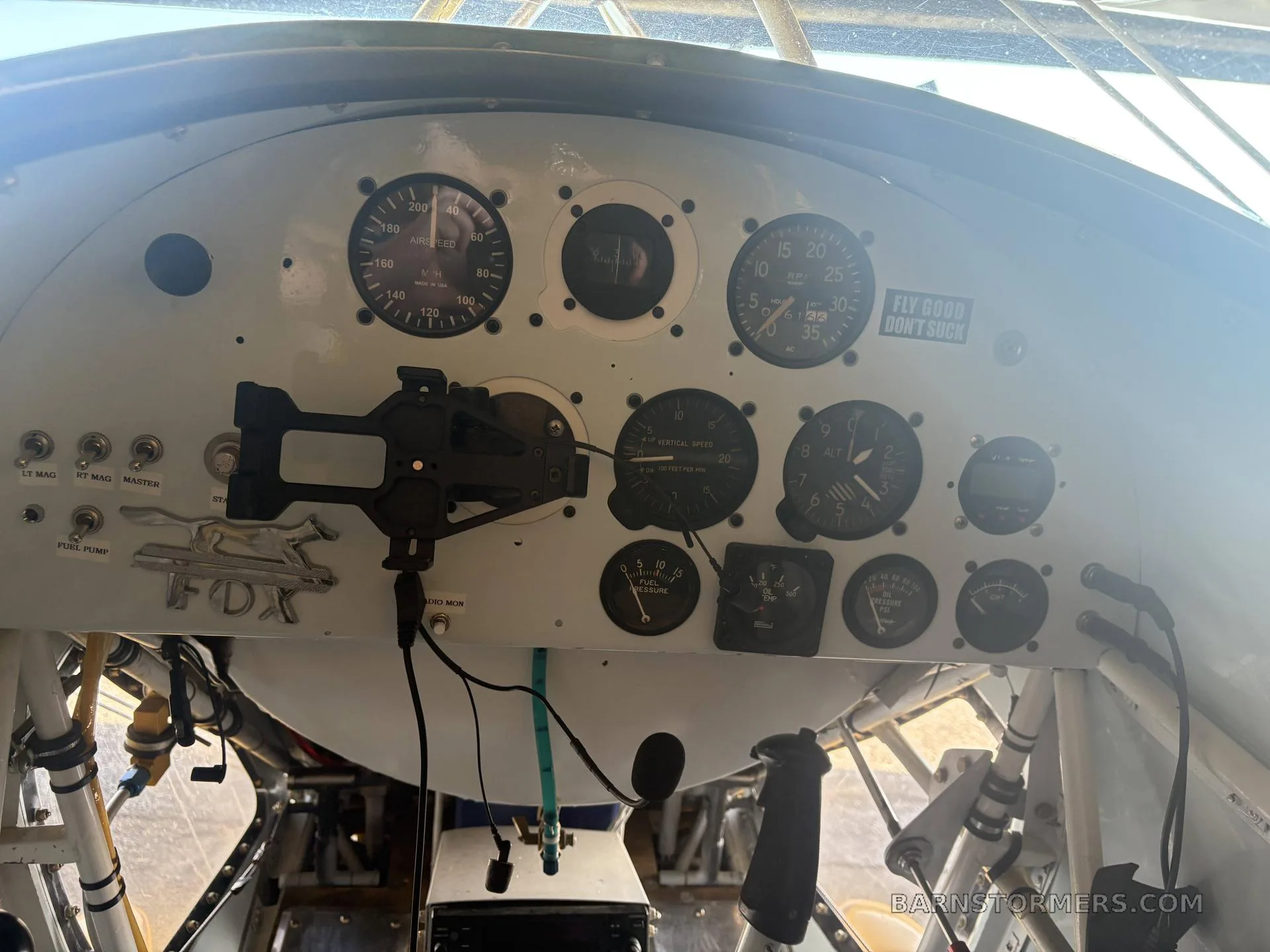 The instrument panel of a yellow biplane, featuring various gauges and a "FLY GOOD DON'T SUCK" sticker.