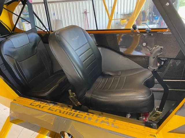 View of the two black seats in the cabin of the yellow Carbon Cub aircraft.