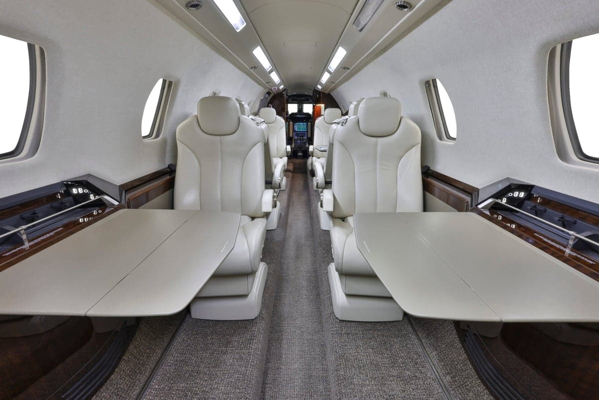 Interior view of the aircraft cabin with seats and tables.