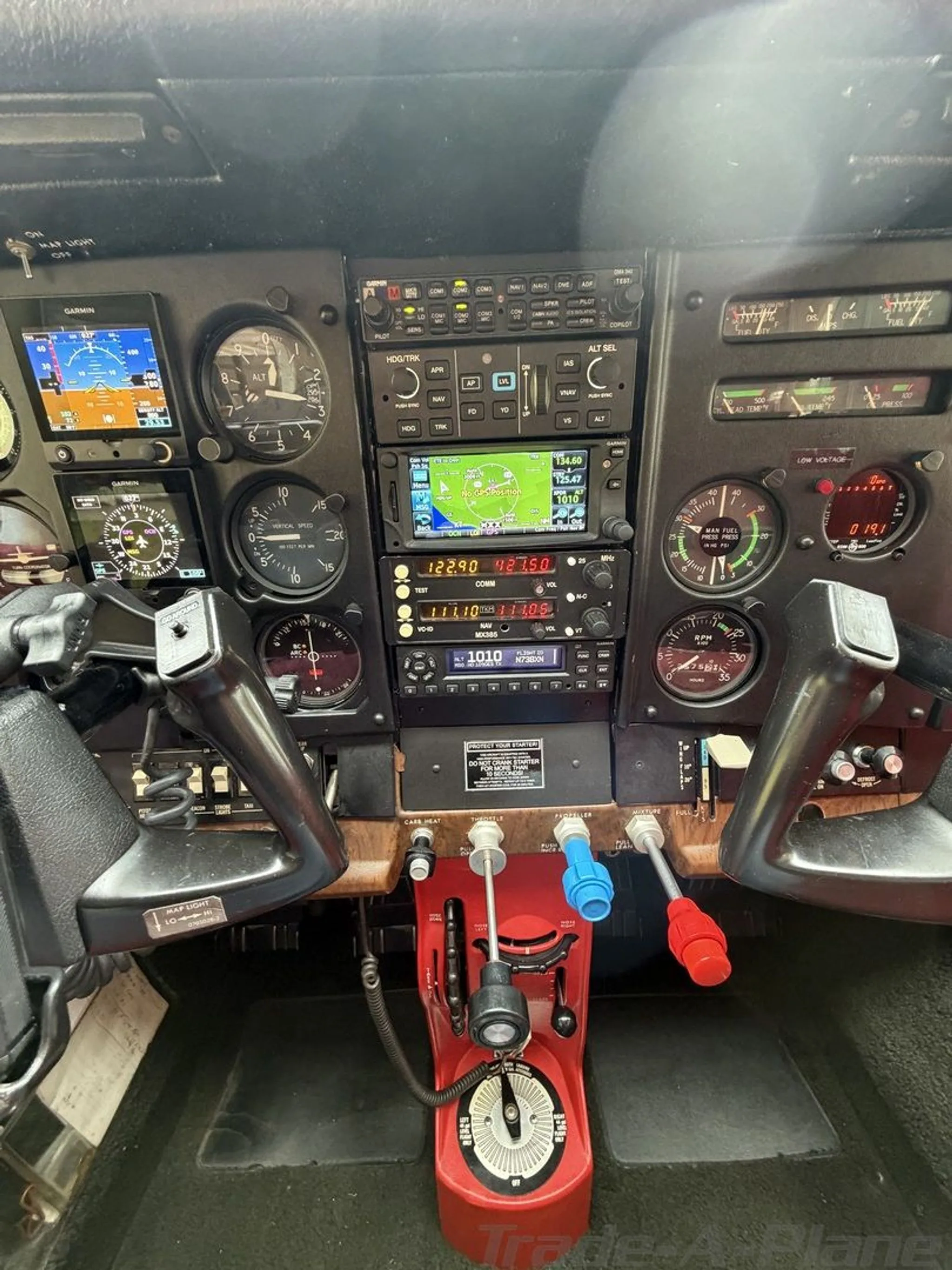 The cockpit instrument panel of a Cessna 182, featuring analog gauges and modern Garmin displays.