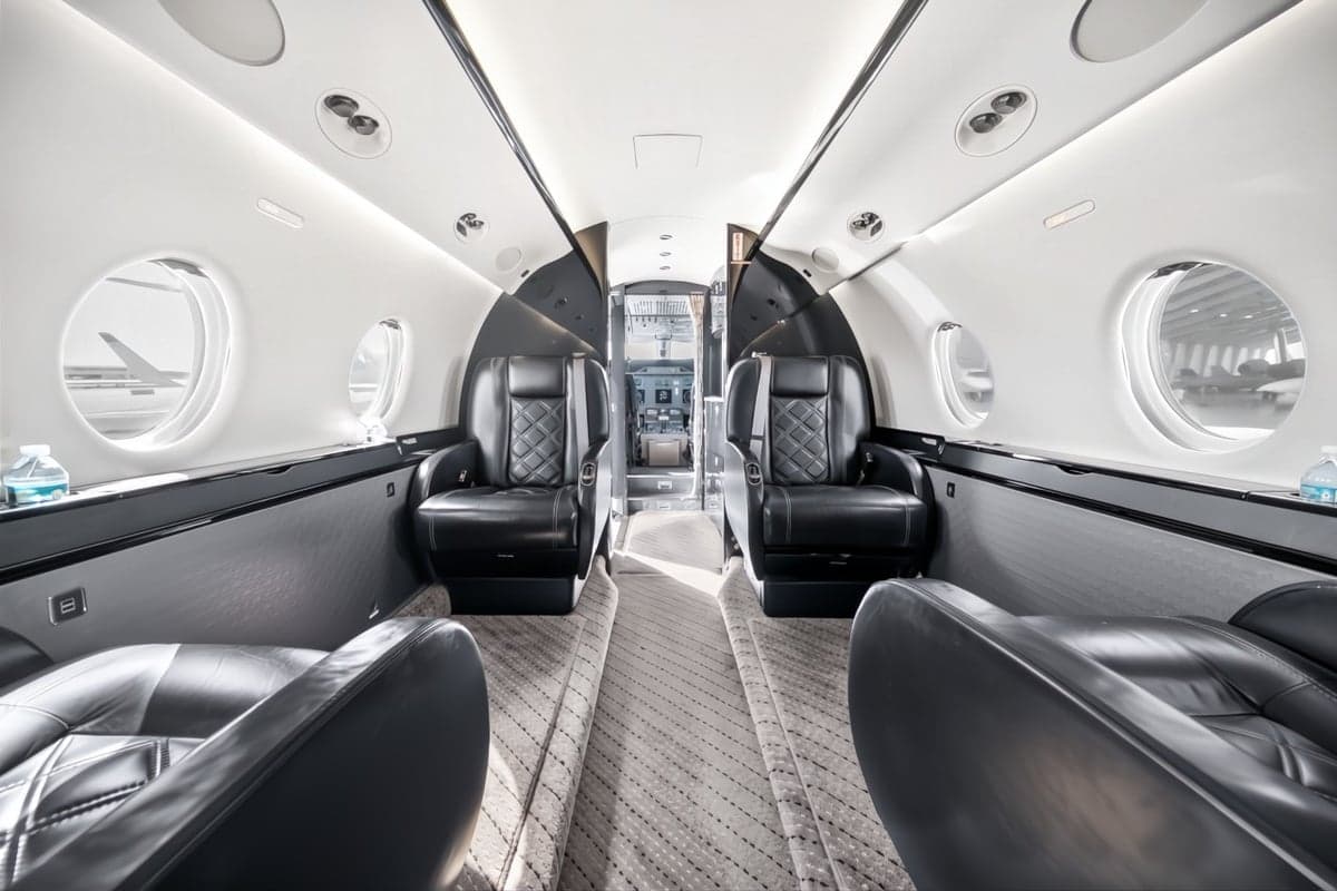 A view of the interior of the aircraft, showing the leather seats and the cockpit.