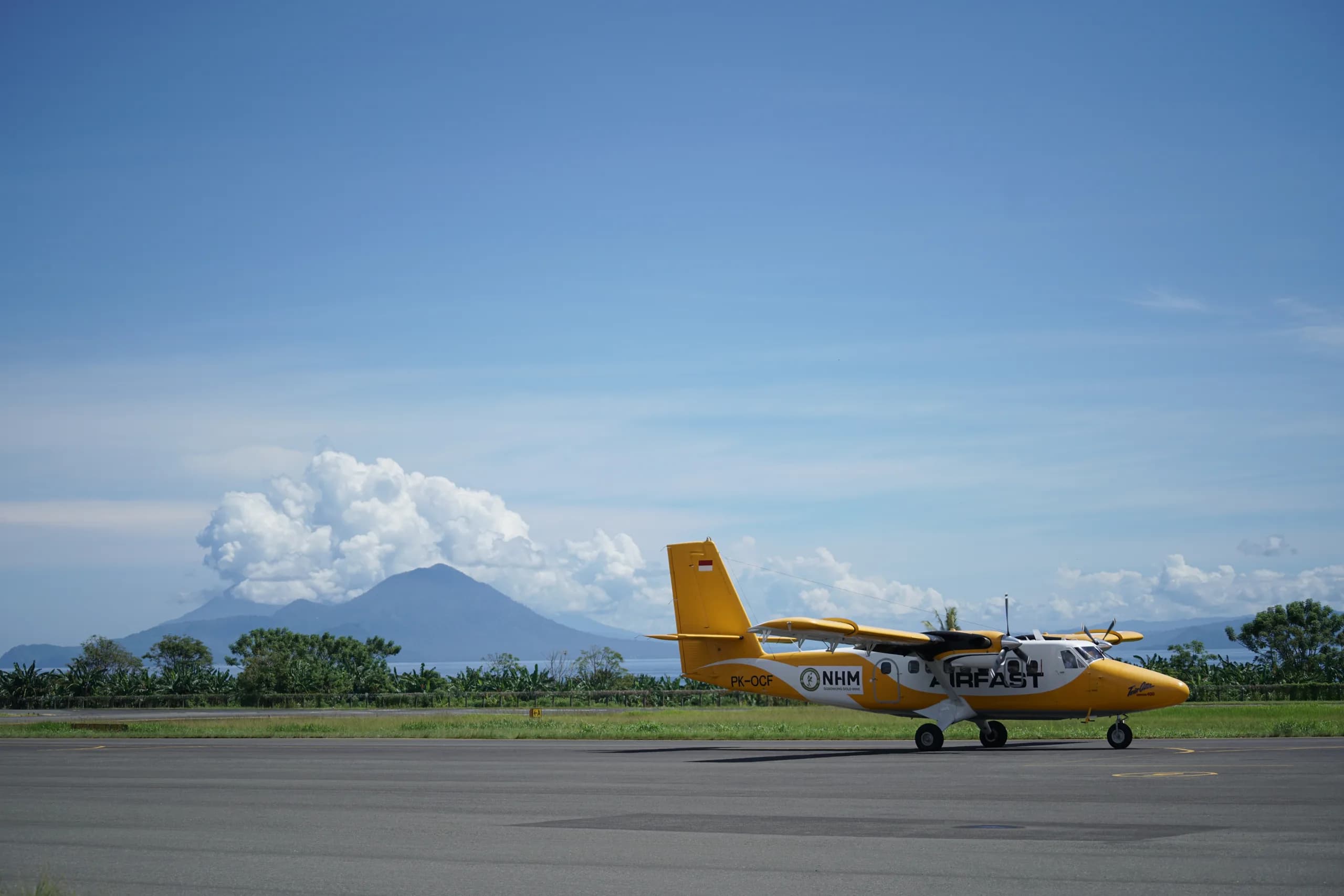 PK-OCF Twin Otter on the tarmac with a volcano in the background.