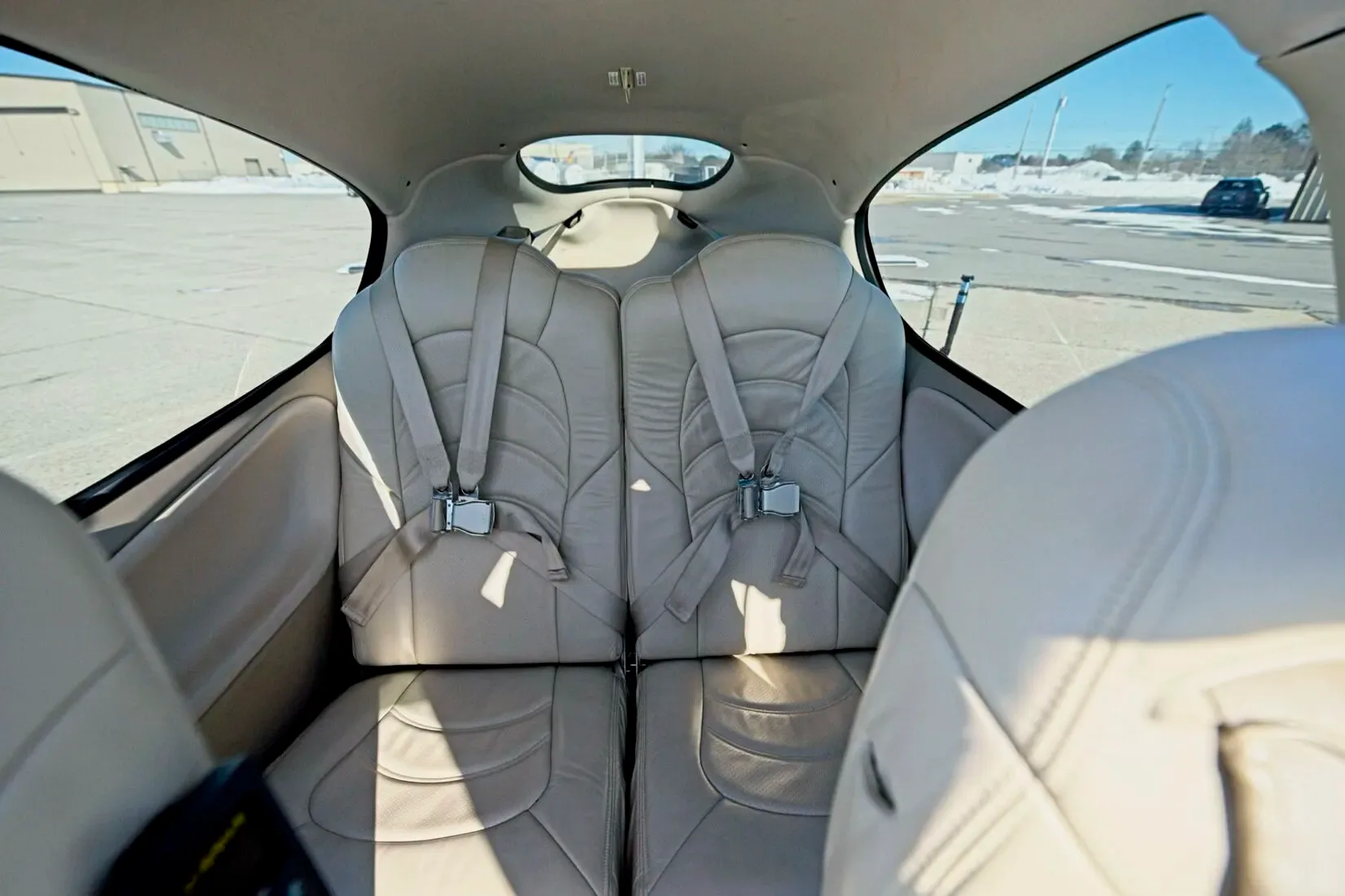 The light tan leather rear seats of a Cirrus SR22 aircraft cabin, viewed from the front.