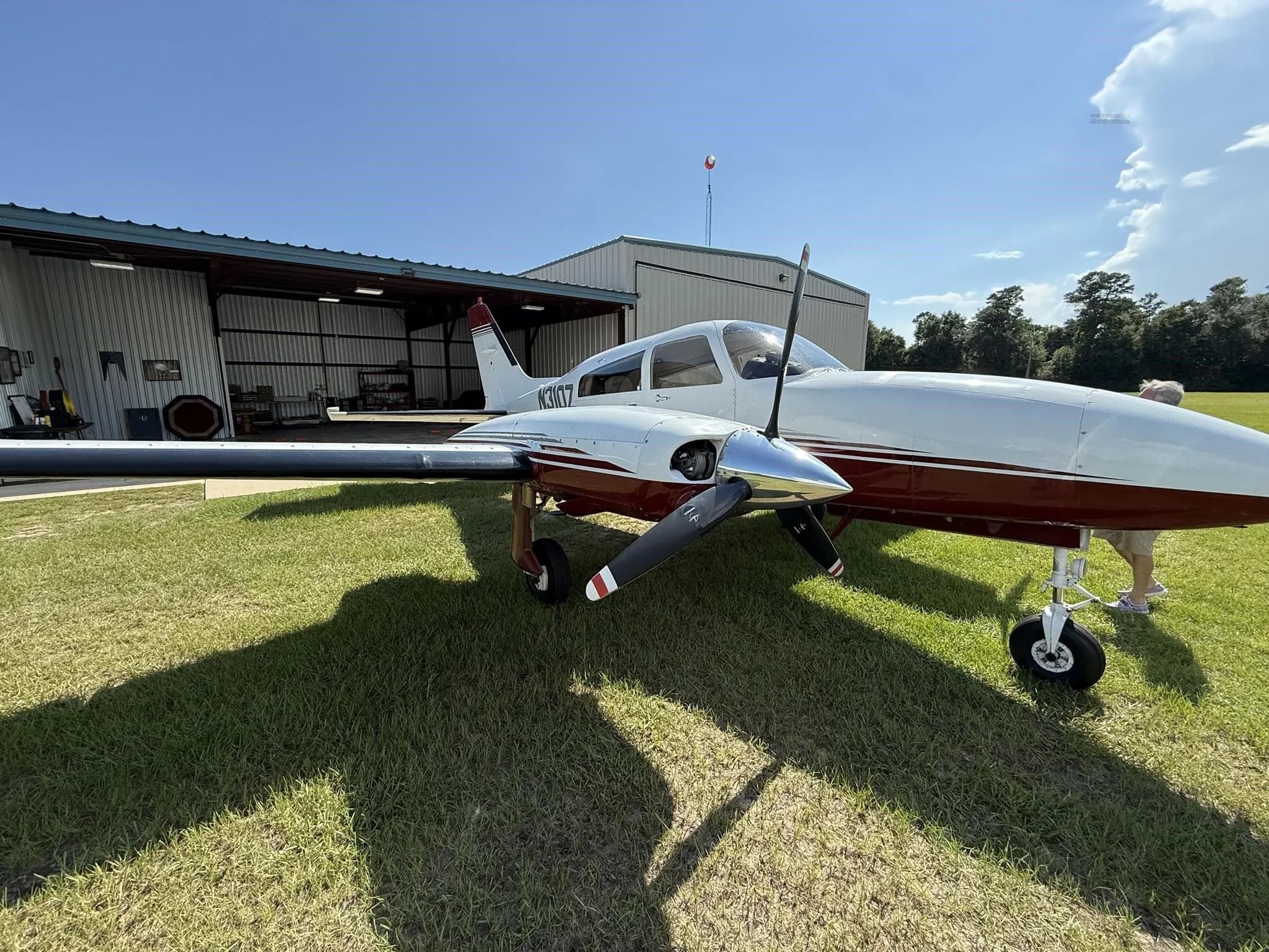 Front-right view of a white and red twin-engine aircraft (N310Z) parked on grass next to a hangar.