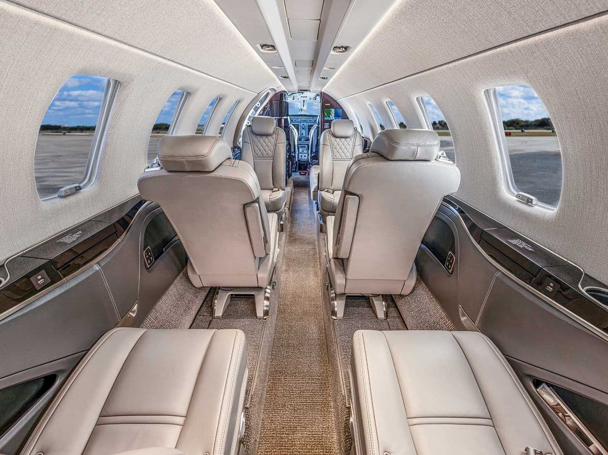 View of the Citation CJ4 cabin featuring gray leather seats and light-colored carpet.
