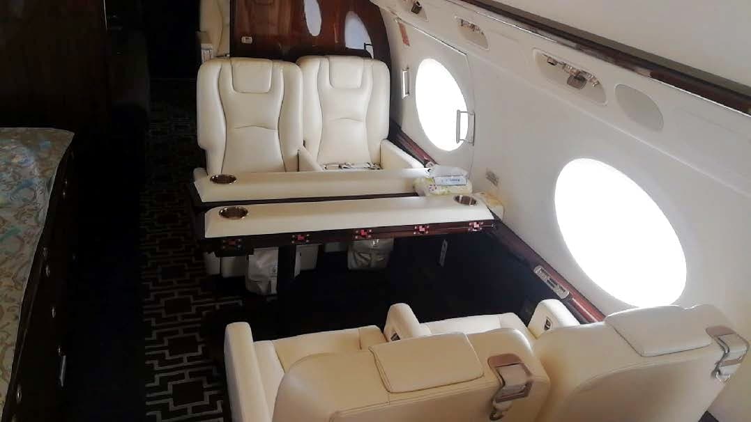 Interior view of the aircraft cabin with cream-colored leather seats and dark wood trim.