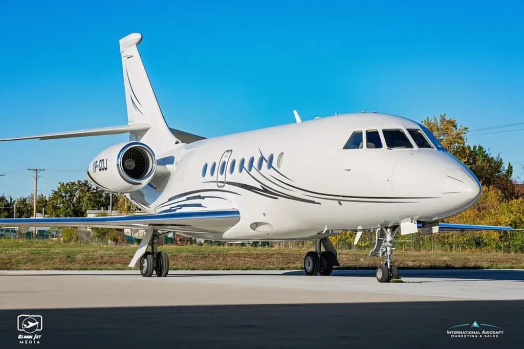 A front-side view of a white Dassault Falcon business jet with black and silver livery, registration VP-CDJ, parked on an tarmac.
