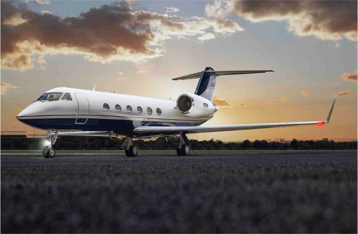 A Gulfstream G550 sits on the tarmac at sunset.