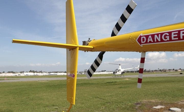 Yellow Robinson R22 helicopter in flight with registration VH-HKT.