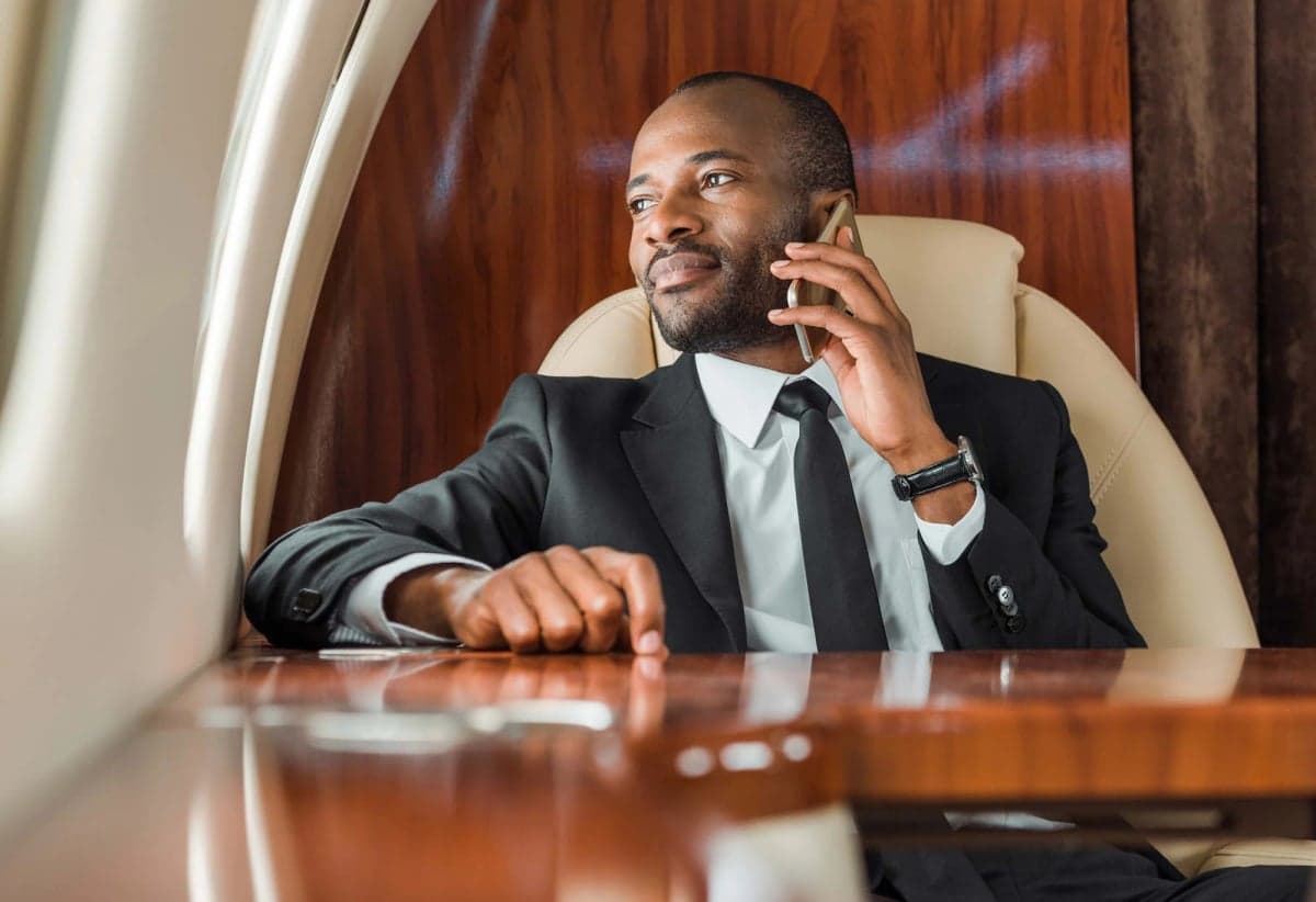 A man sits in a leather seat inside a private jet.