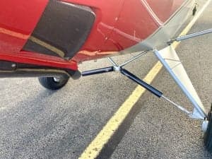 Close-up of the landing gear of the red and silver Carbon Cub N7XU.