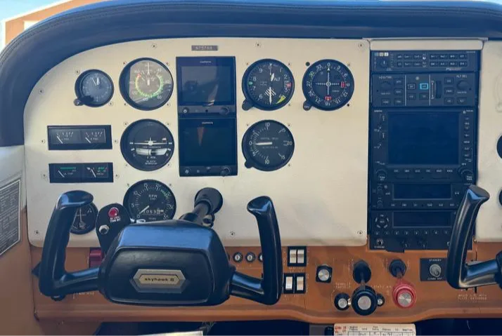 The cockpit instrument panel of a Skyhawk II aircraft, showing gauges, avionics, and yokes.