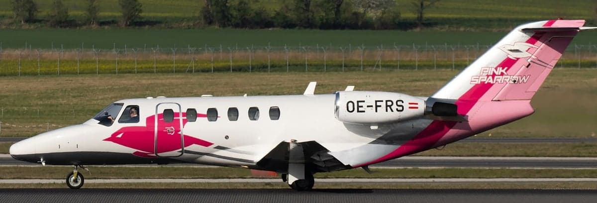 OE-FRS aircraft with pink and white paint scheme on the runway.