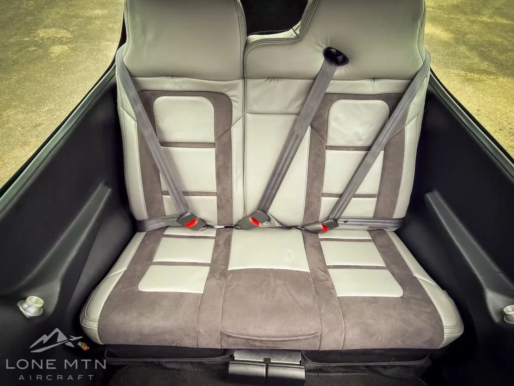 The gray and light gray rear seats of an aircraft cabin with seatbelts.