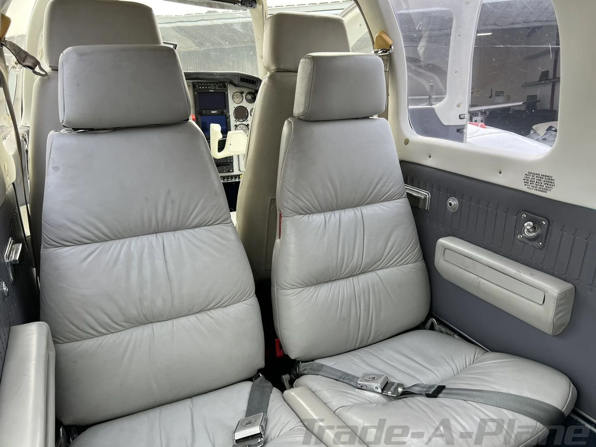 The light gray leather passenger seats in the cabin of the N5177M aircraft, with the cockpit visible in the background.