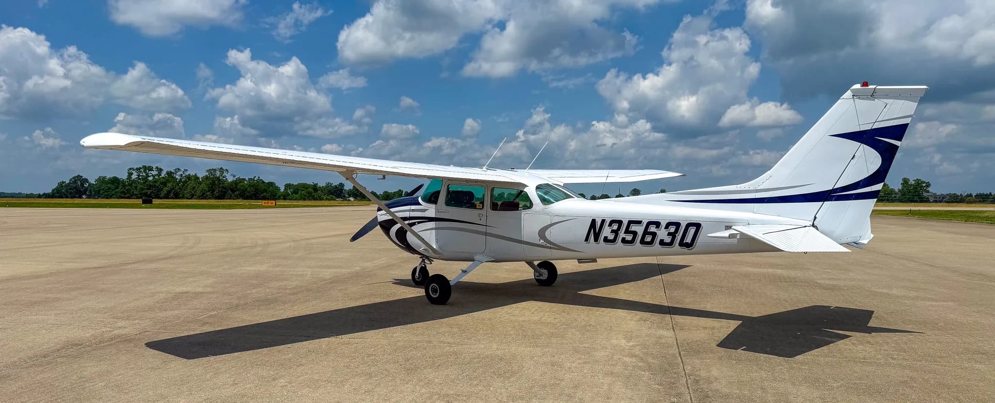 Right-rear view of a white and blue Cessna 172 with registration N3563Q on an airfield.