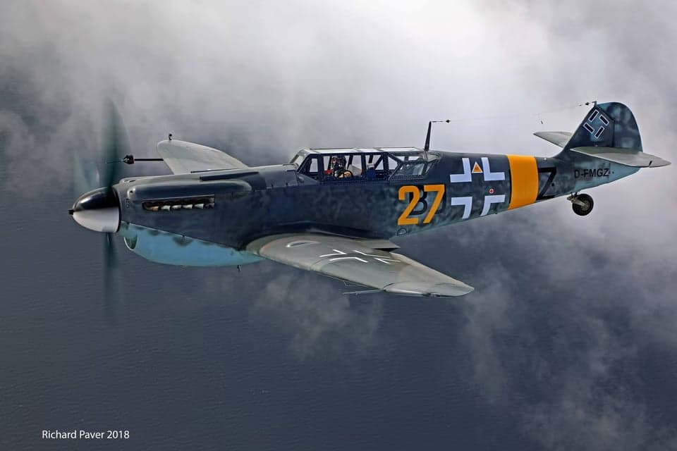 Overhead view of a Messerschmitt Bf 109 in flight over water.