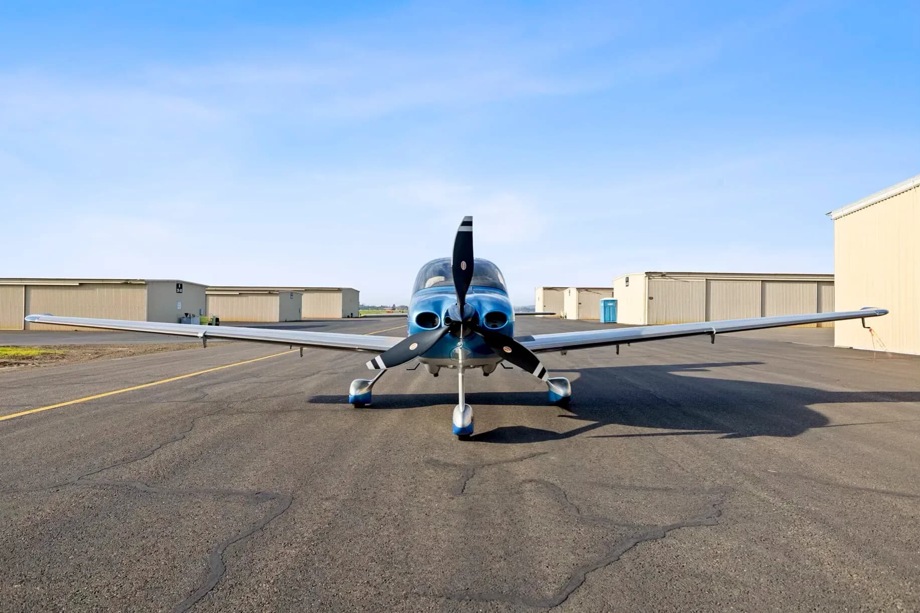 A front view of the blue and silver Cirrus SR22T aircraft parked on an airfield.